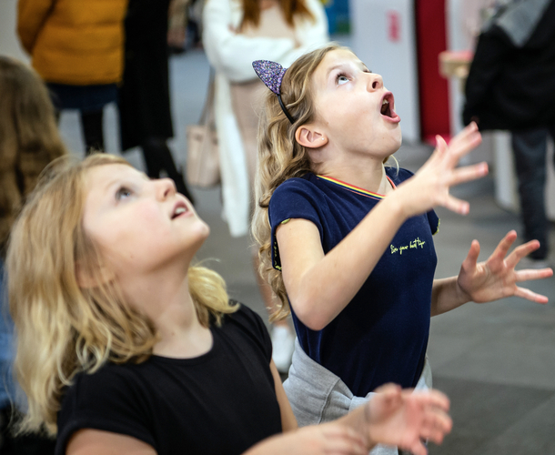 Interactive science exhibition photo showing two girls looking up at an exhibit expressing amazement