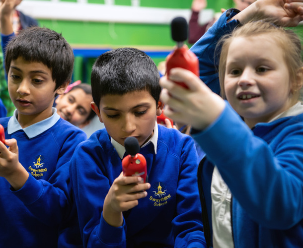 Three school children measuring noise levels using sound readers