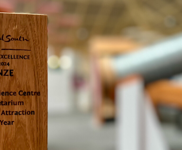 A wooden award in front of some Science Centre exhibit