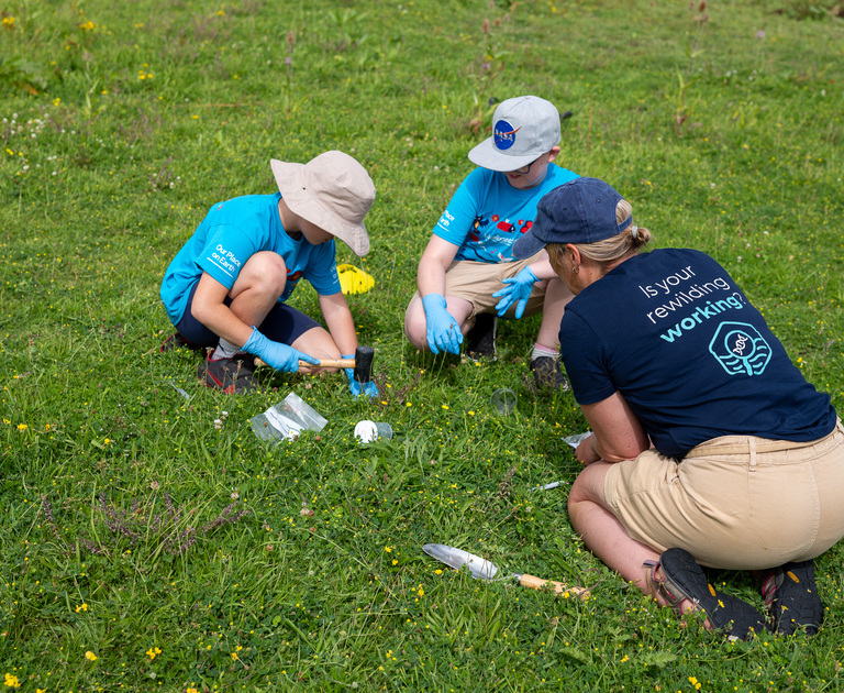 Two children are taking soil samples in the South Downs lawn at Winchester Science Centre.