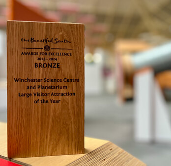 A wooden award in front of some Science Centre exhibits