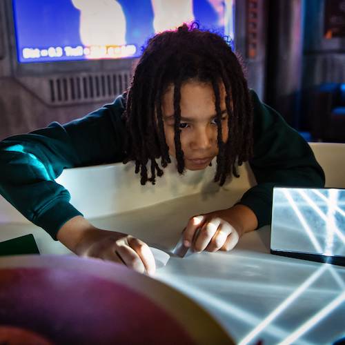 Interactive science exhibition photo showing a student leaning over the edge of an exhibit