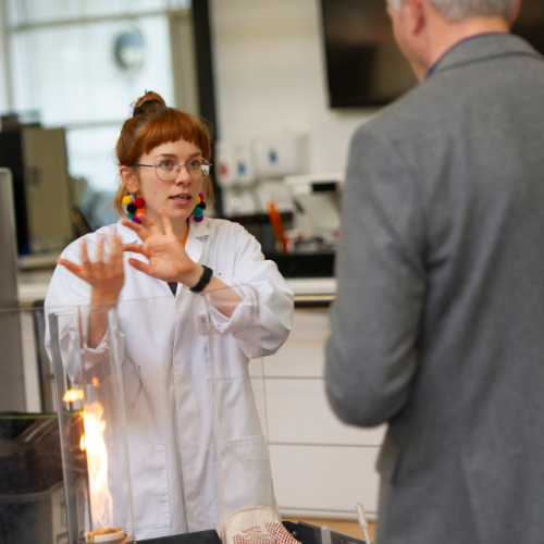 A teacher in a lab coat talking to a man in a suit