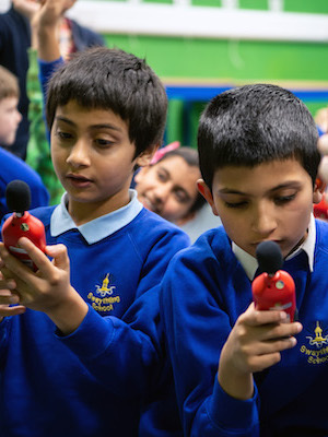 Two school children holding noise level meters into the air to get a measurement