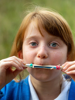 A young girl testing out a harmonica she has made