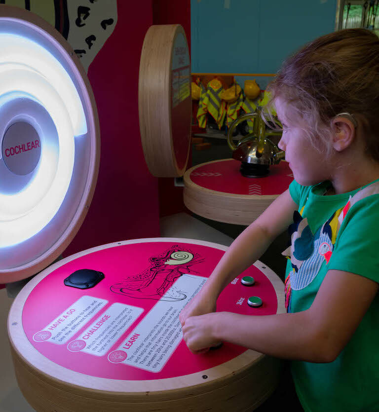 Interactive science exhibition photo showing a girl engaging with an exhibit