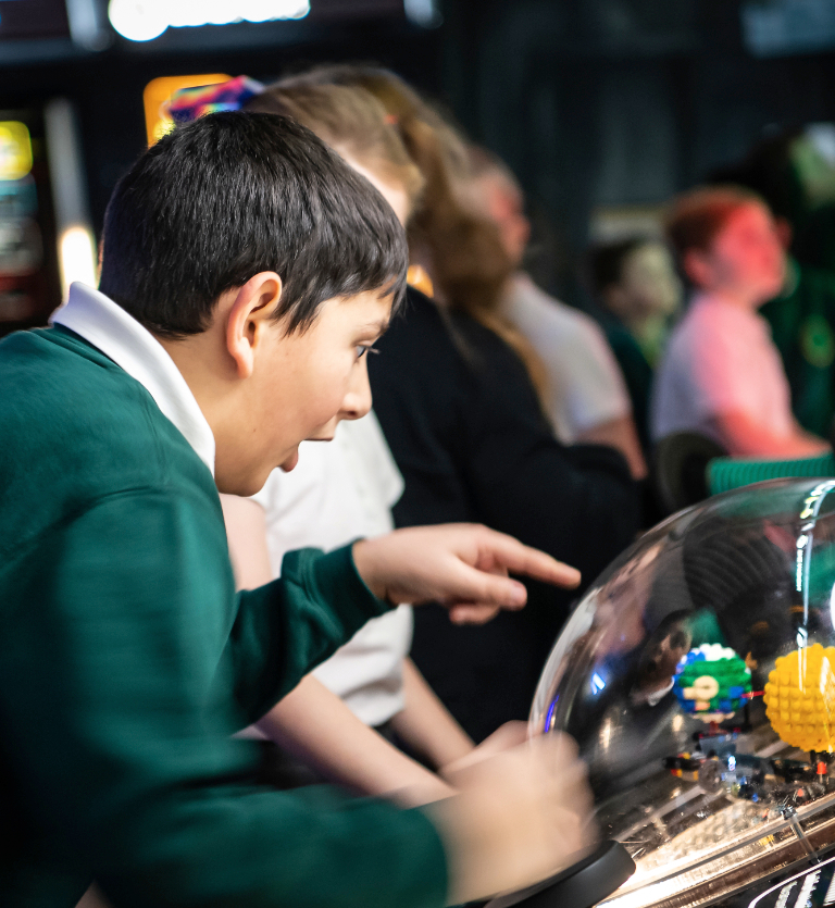 Interactive science exhibition photo showing a boy in school uniform pointing and looking with wonder at an exhibit